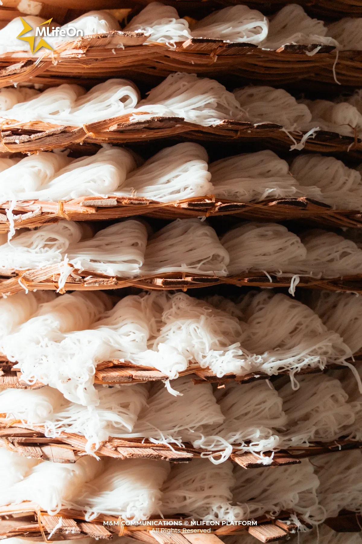 Trays of banh hoi neatly arranged, ready to be steamed over the wood fire.